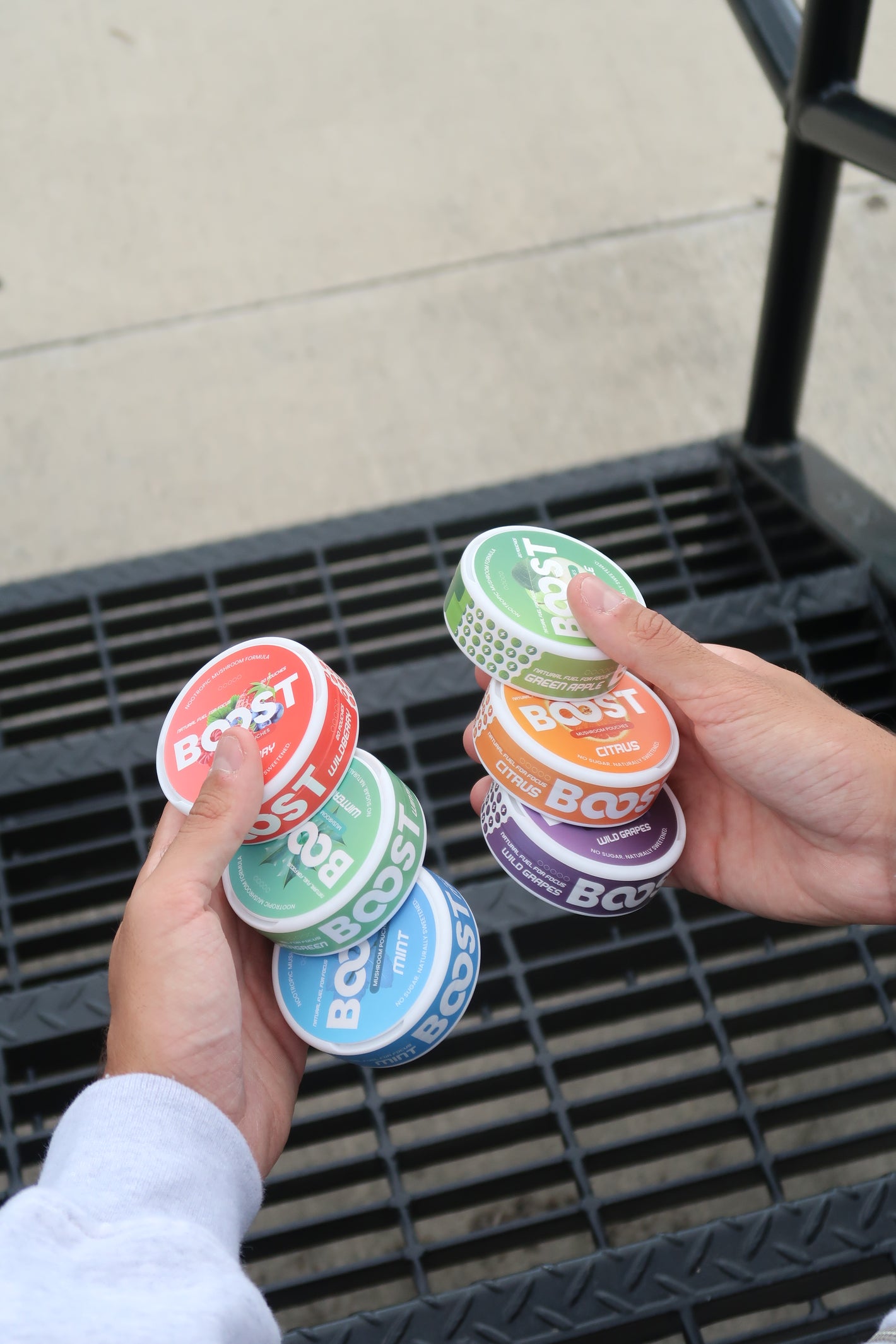 Hand holding colorful Boost energy drink containers with a blurred background
